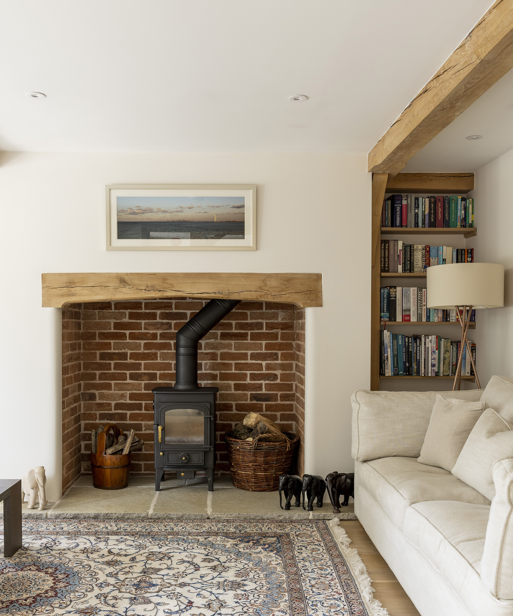 A log burning stove in a fireplace area of a timber frame new build. The living room is cosy with built in shelves