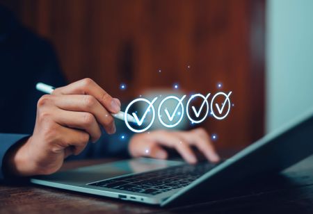 Businessman using digital checklist on laptop with glowing check marks symbolizing task completion, project management, productivity, goals achievement, and successful workflow system.