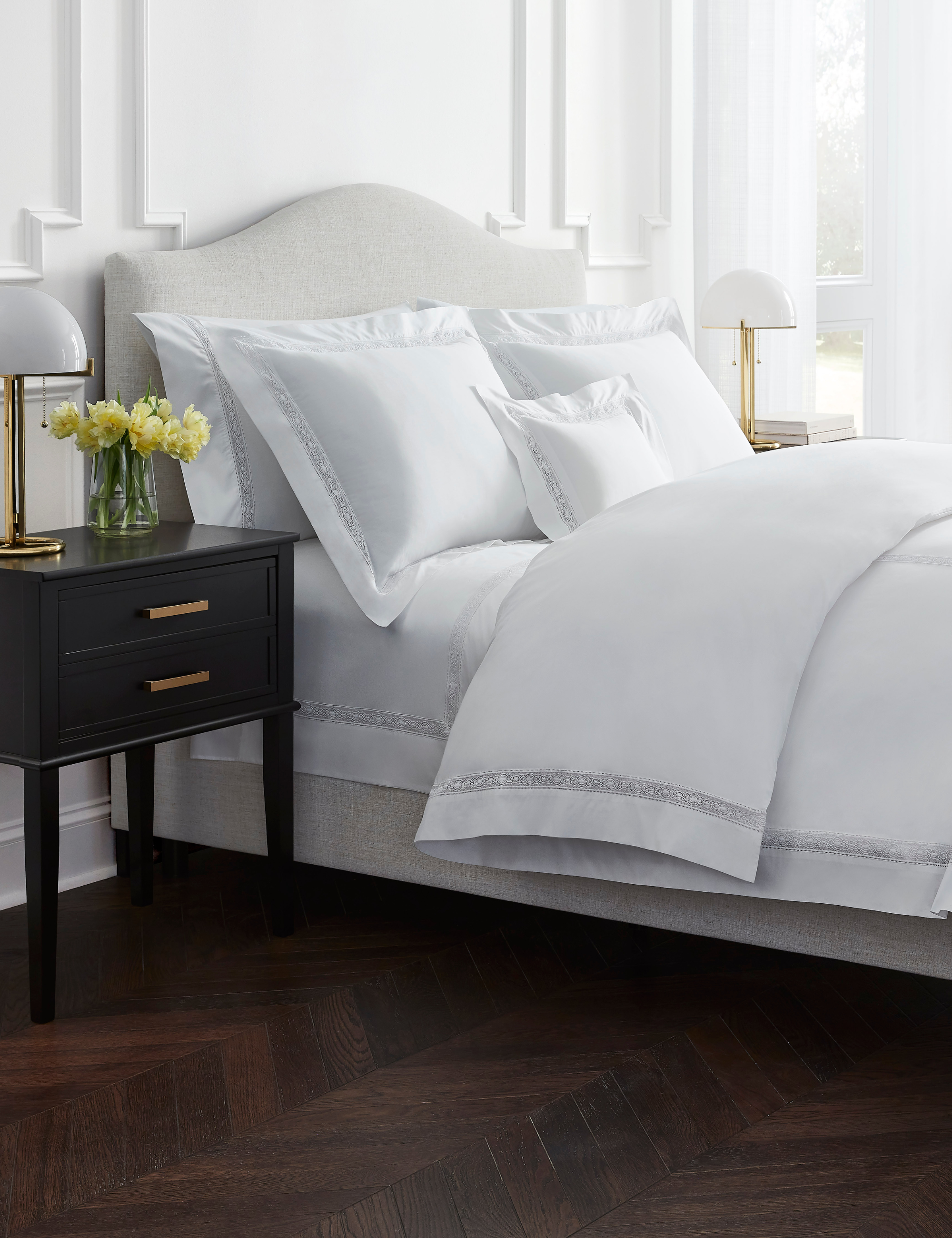 All-white bedroom with ornate molding featuring a bed styled with Sferra Giza 45 Sateen sheets