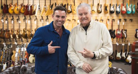 TNAG Global founder/CEO Ben Montague [left] and Norman Harris [right] point to each other as they are photographed on the shop floor at Norman's Rare Guitars.