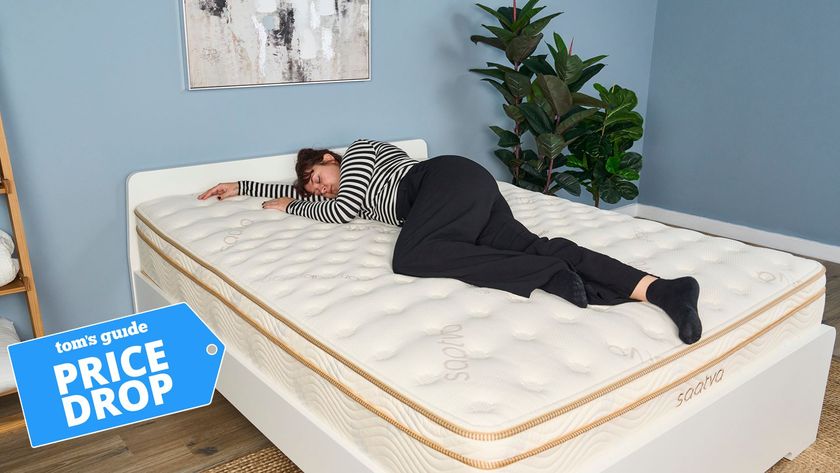 Tom&#039;s Guide mattress tester lying on her side on the Saatva Classic mattress in a blue-painted bedroom