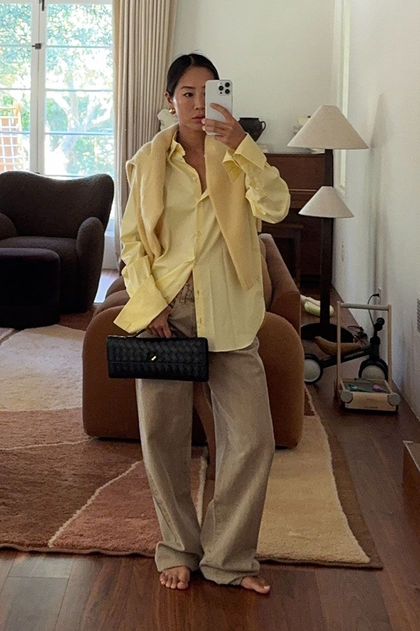 a woman holding a top handle clutch bag