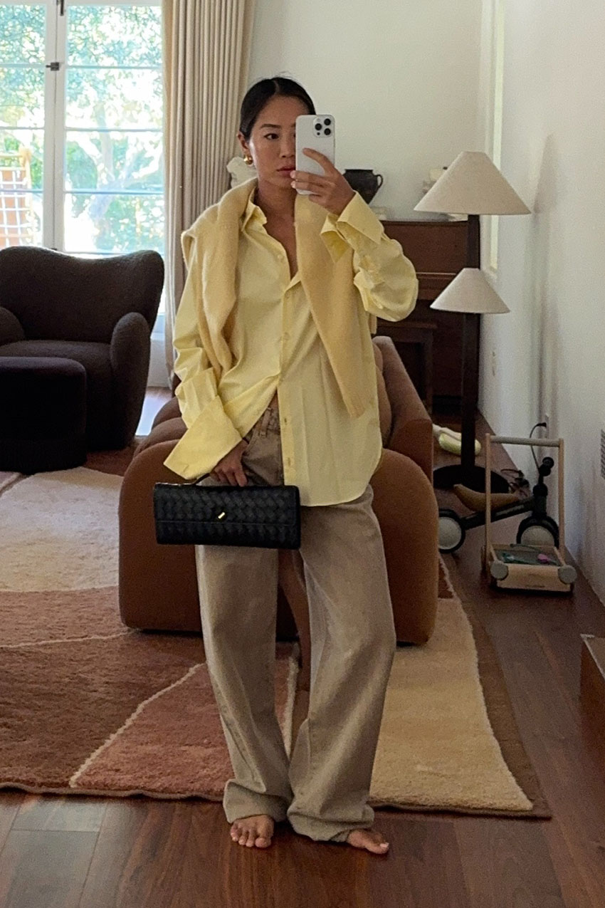 a woman holding a top handle clutch bag