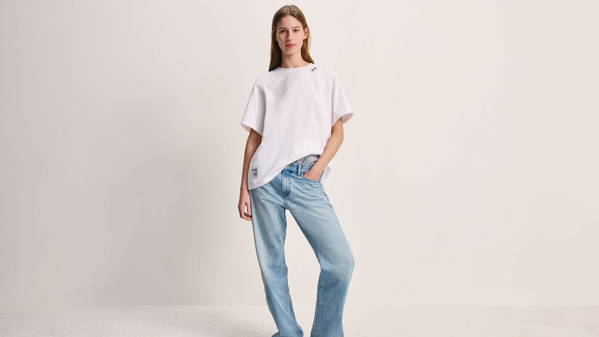 a model wearing jeans and a white t-shirt from the uniqlo anya hindmarch collaboration
