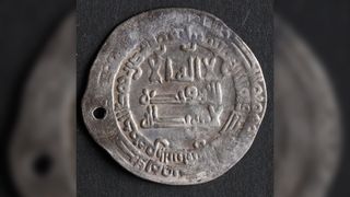A silver coin with Arabic writing on it.