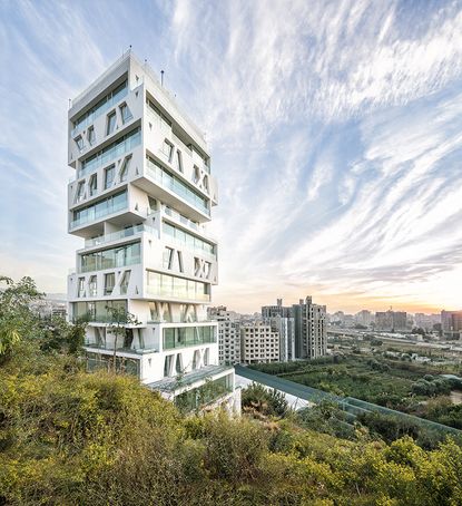 The Cube by Orange Architects, rises majestically above its surroundings like an asymmetrical urban lighthouse