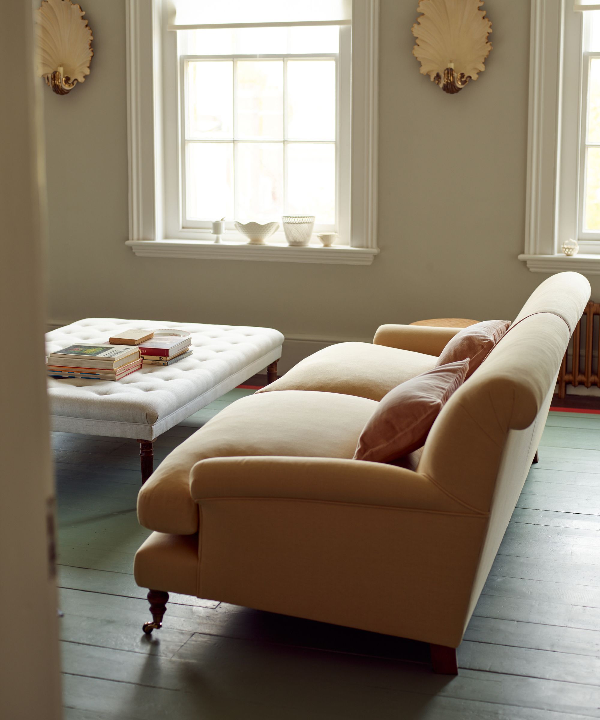 A large straw coloured sofa on casters