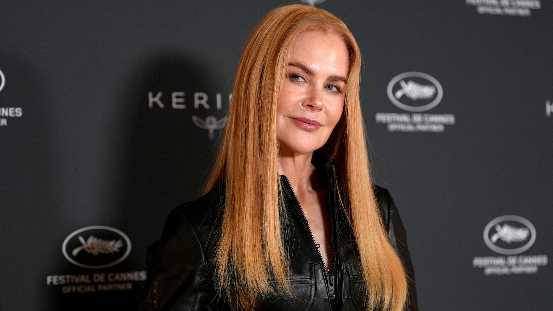 Nicole Kidman with strawberry blonde long straight hair and wearing a black leather shirt