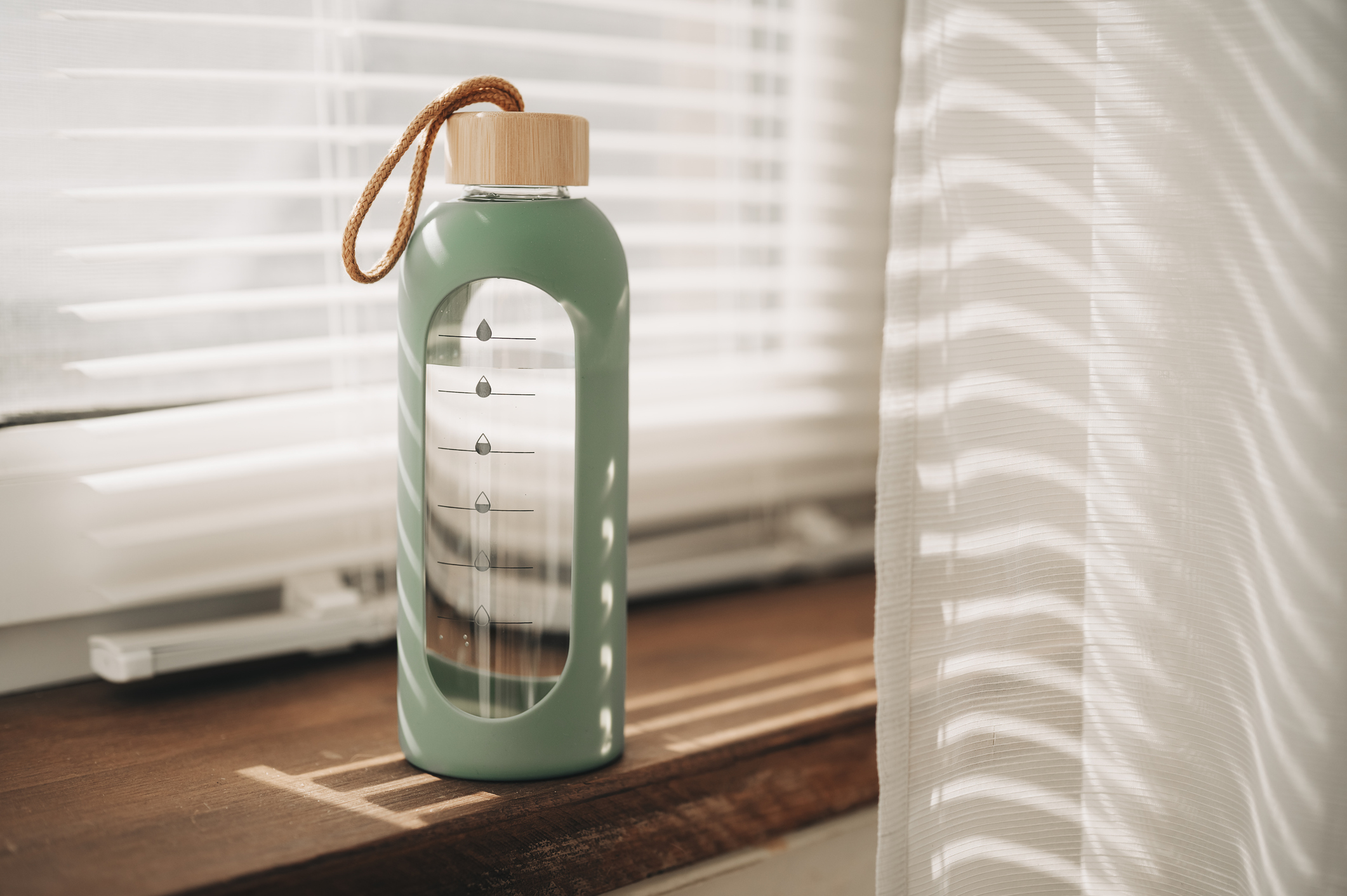 A blue and pink reusable water bottle on a wooden window sill.
