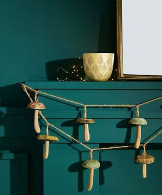 mushroom garland on a green mantelpiece with mirror and brass accessories - anthropologie