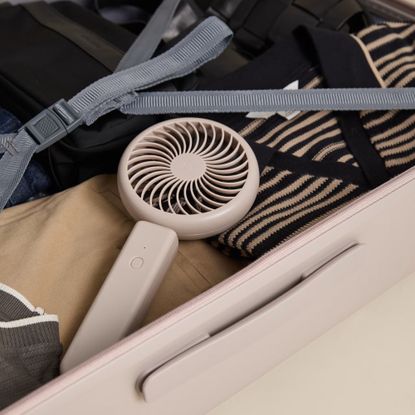 Portable fan from M&S in beige, sitting in a suitcase with clothes