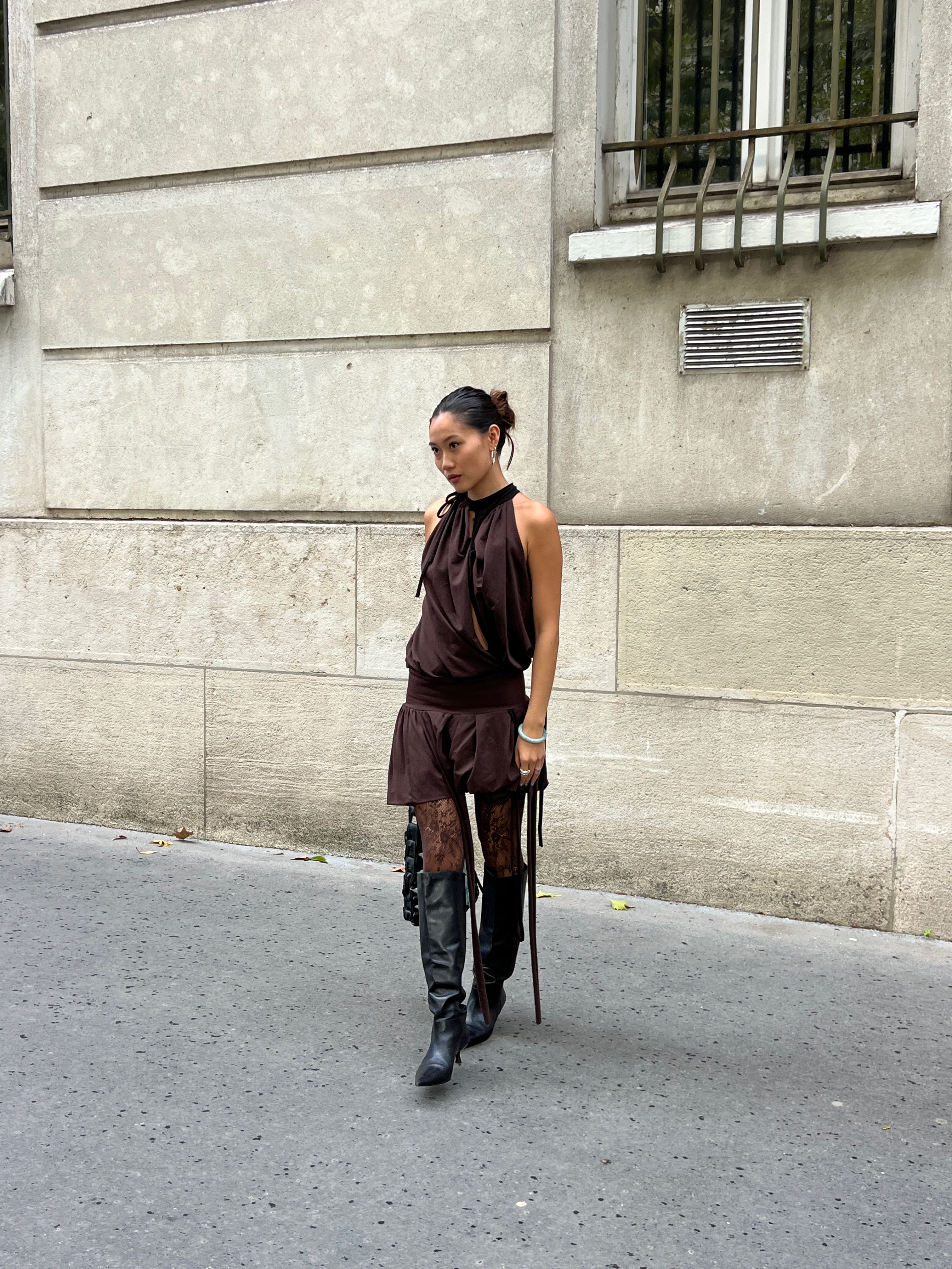 Vivian Li wearing brown lace, a brown silk dress, and black boots in a Paris Fashion Week outfit.