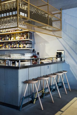 A bar painted to match the walls, with natural wooden bar stools