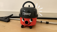 Henry HVR160 Vacuum Cleaner on a wooden background with an animation around the top