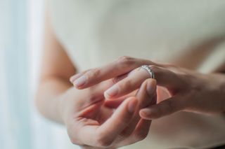 A close up of a woman sliding her simple silver wedding ring onto her finger.