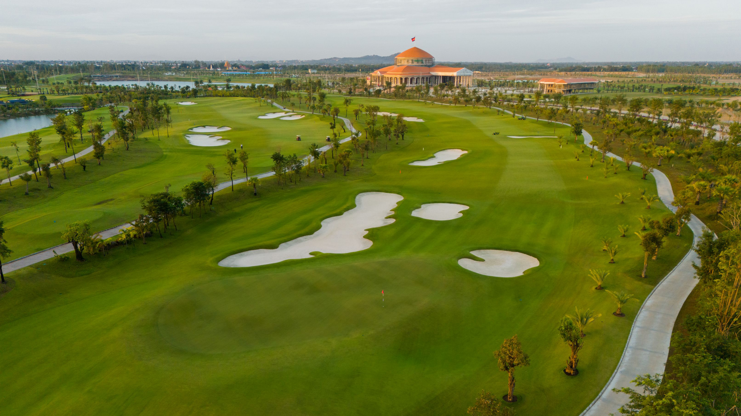 A hole at Chhun On Golf Club and the clubhouse in the background