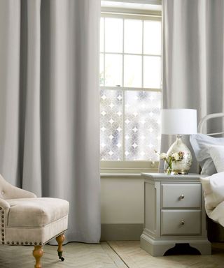 Contemporary gray bedroom with patterned window film and gray curtains