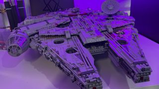 A fully-built Lego UCS Millennium Falcon, sat on a table and bathed in purple light