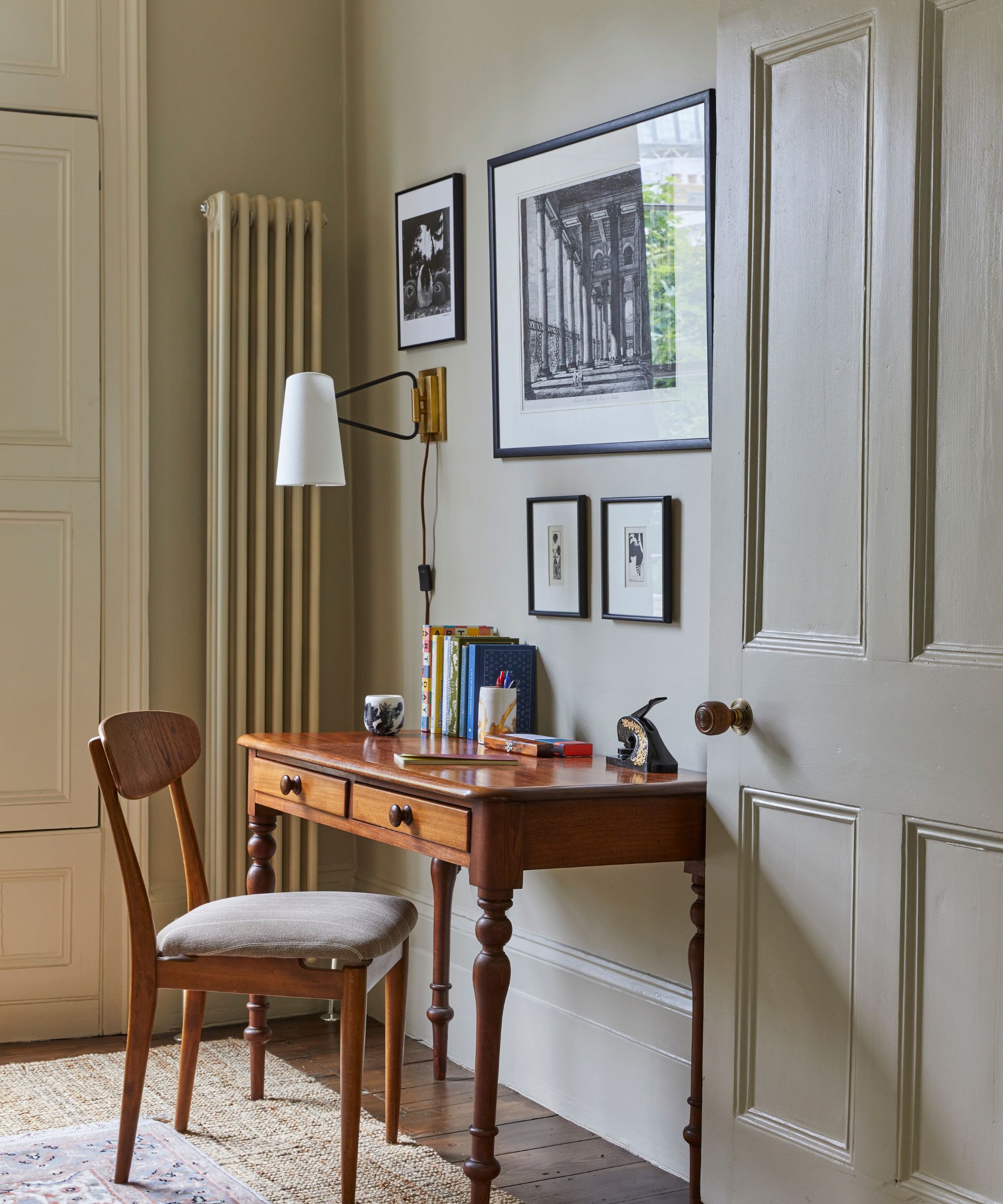 Study with antique wood desk and chair, sconce, vintage prints and rug