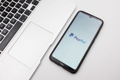 Smartphone displaying a PayPal logo next to a laptop