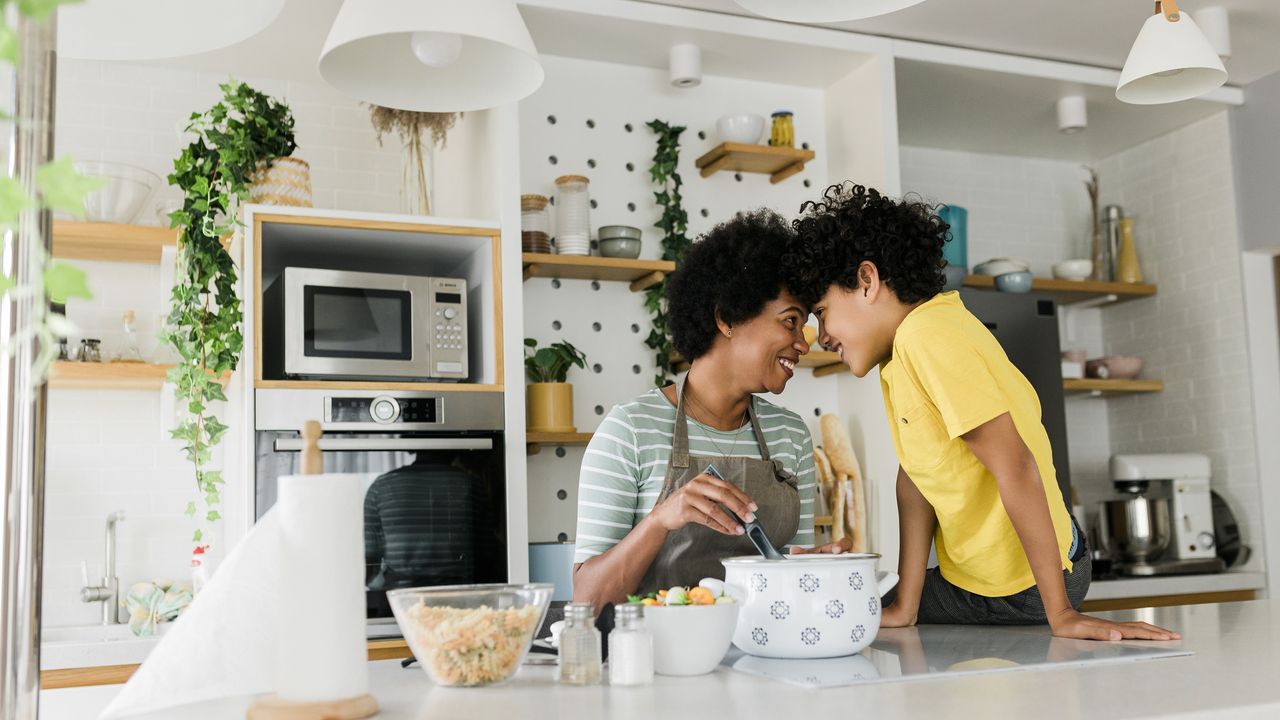 A mom and her young son cook together in the kitchen.