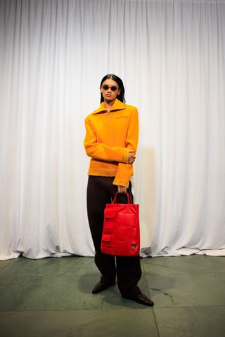 A photo of a model holding a red Tory Burch cargo tote bag.