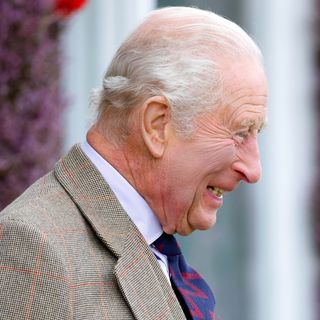 King Charles smiling in a suit and blue tie