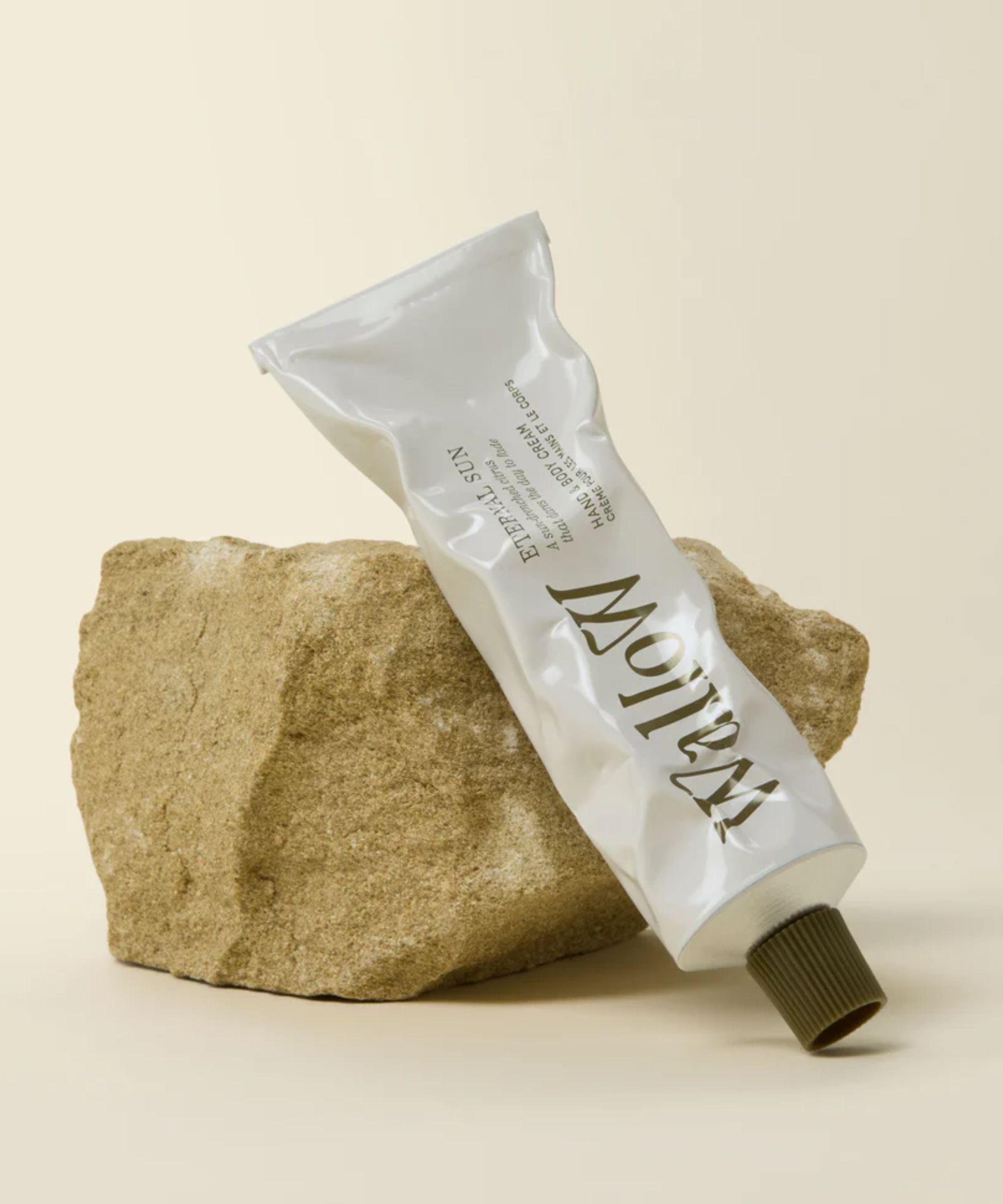 White hand cream bottle leaning against a small rock