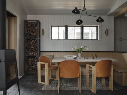 a contemporary dining area with wood logs on display with banquette seating