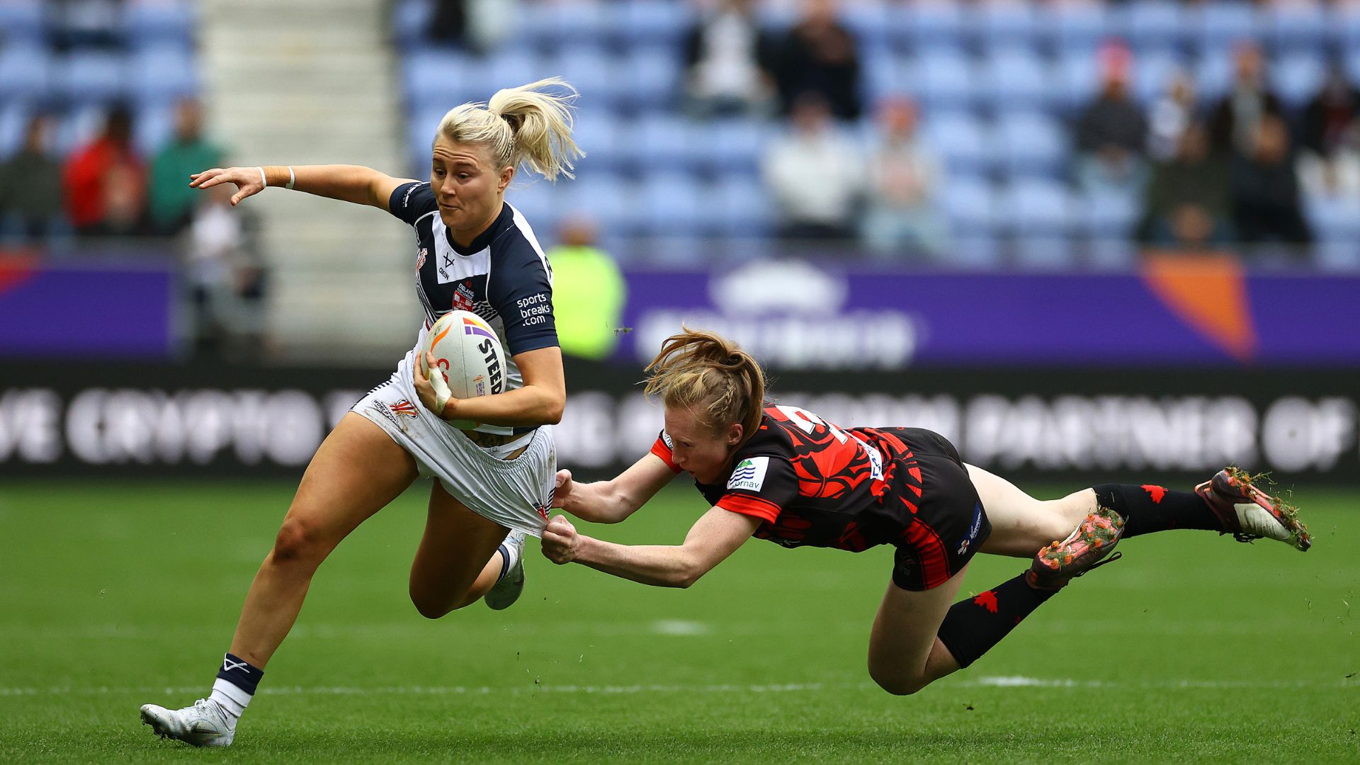 WIGAN, ENGLAND - NOVEMBER 05: Tara-Jane Stanley of England is tackled by Petra Woods of Canada during the Women's Rugby League World Cup Group A match between England Women and Canada Women at DW Stadium on November 05, 2022 in England