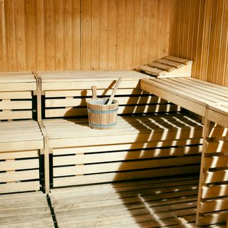 Wooden sauna with two benches and wooden bucket