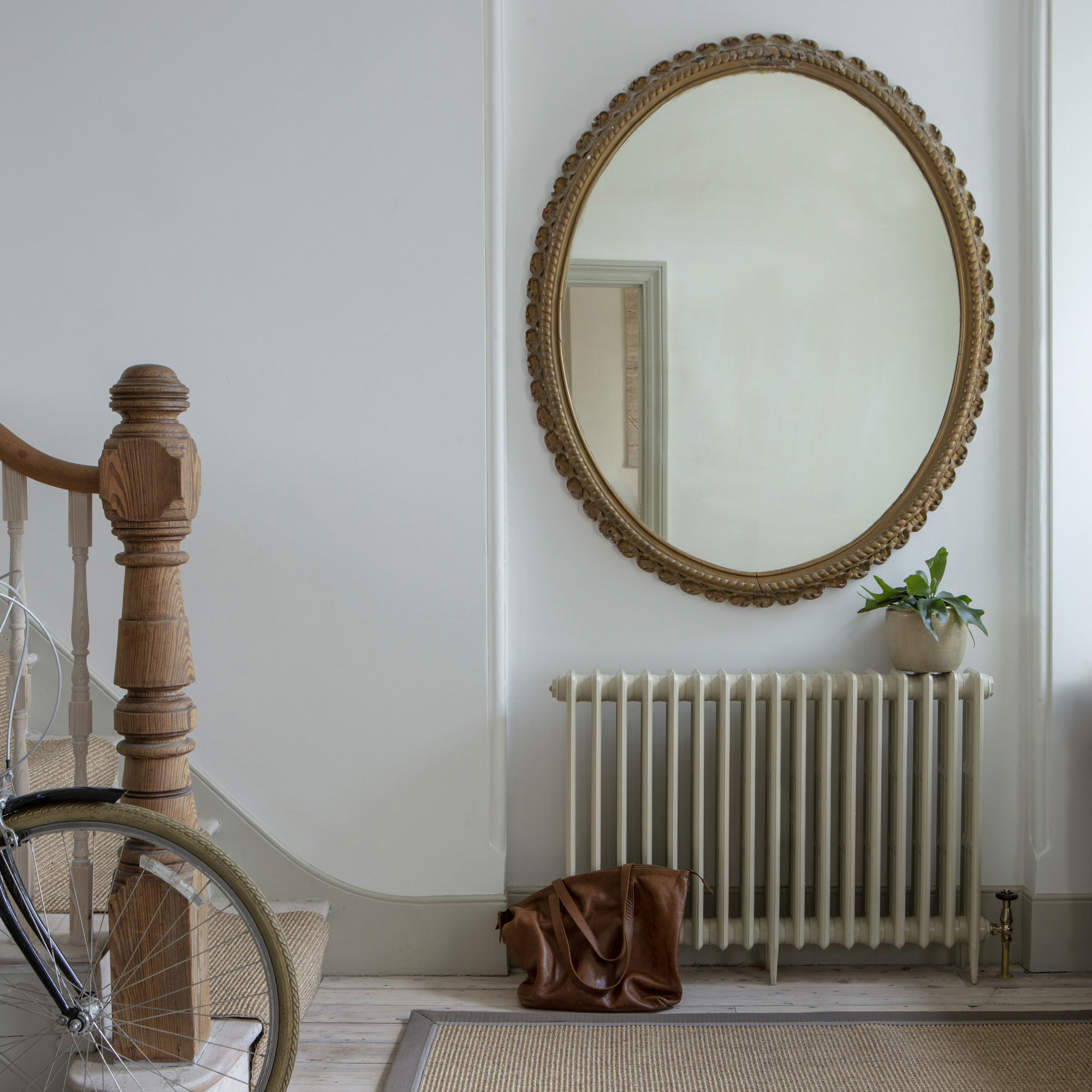 White hallway with massive mirror and radiator
