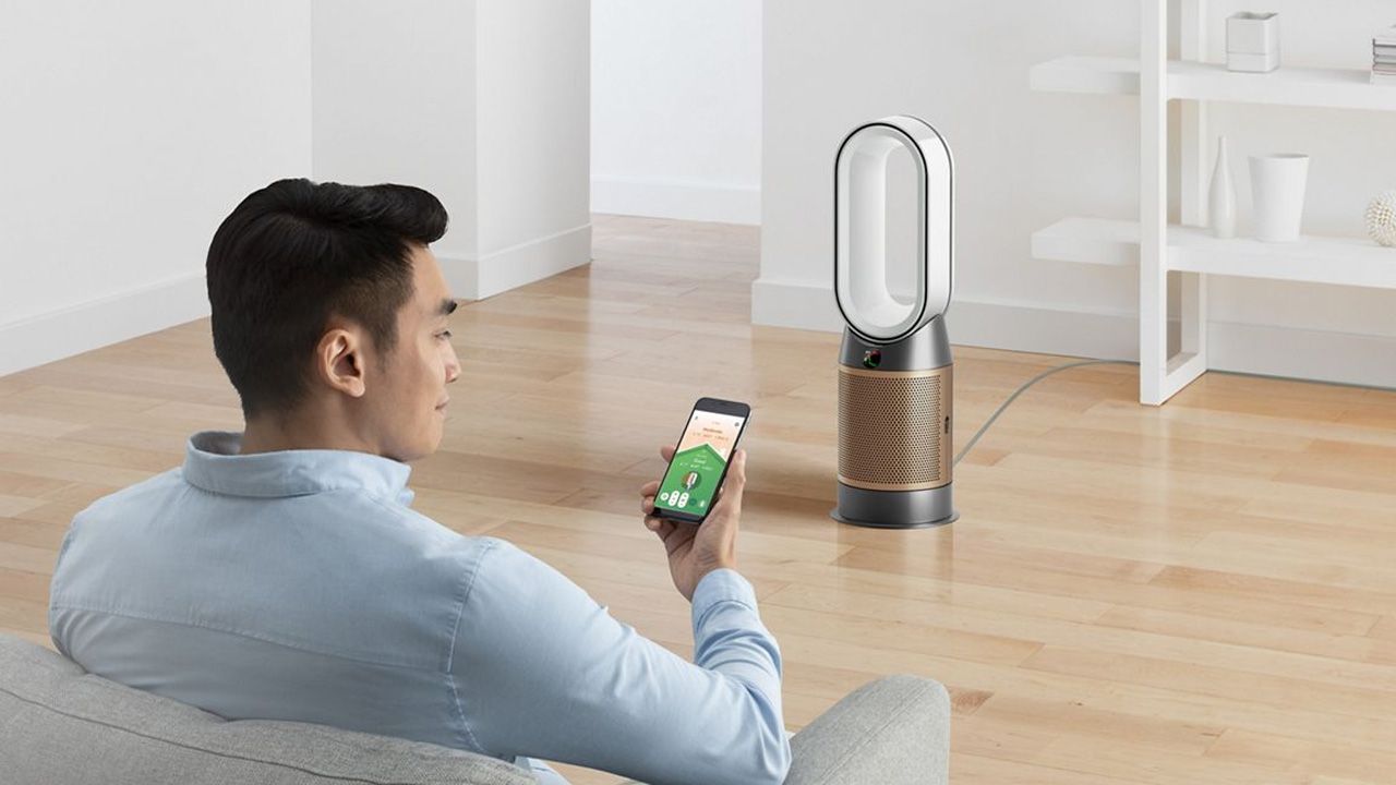 Dyson Purifier Hot+Cool Formaldehyde HP09, a man looking at the Dyson app on his phone while the purifier sits on the wooden floor.