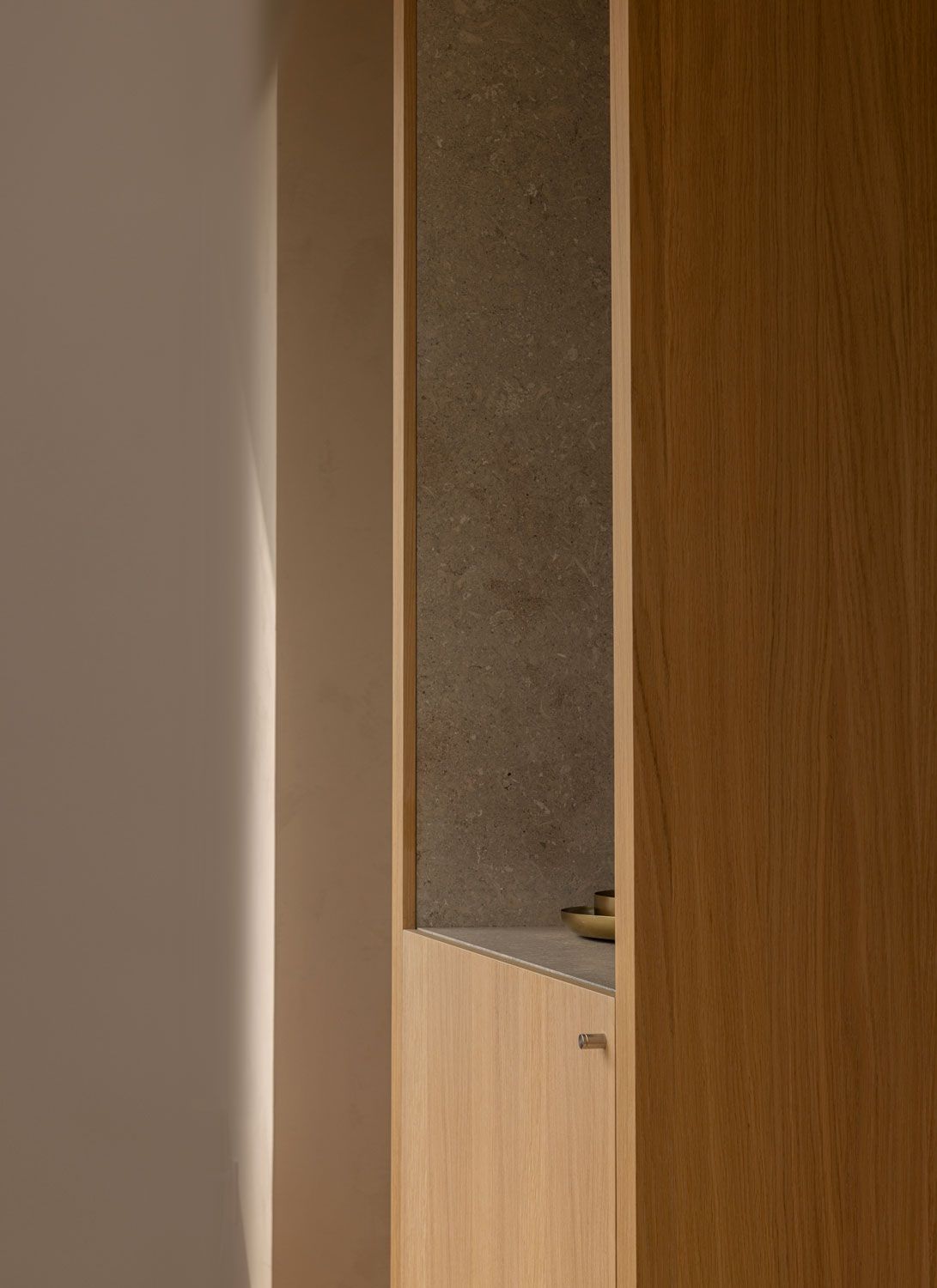 Close-up of bespoke oak cabinetry at 262 Fifth Avenue by Norm Architects, with a recessed stone niche and integrated storage
