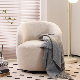 A swivel boucle accent chair in a neutral living room with checkered floor