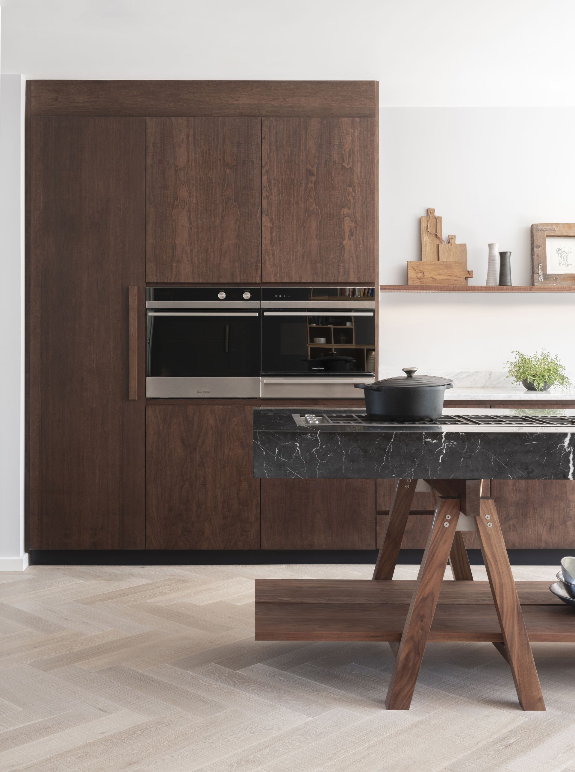 Kitchen with dark wood cabinets and island with hob, wood floor and white walls
