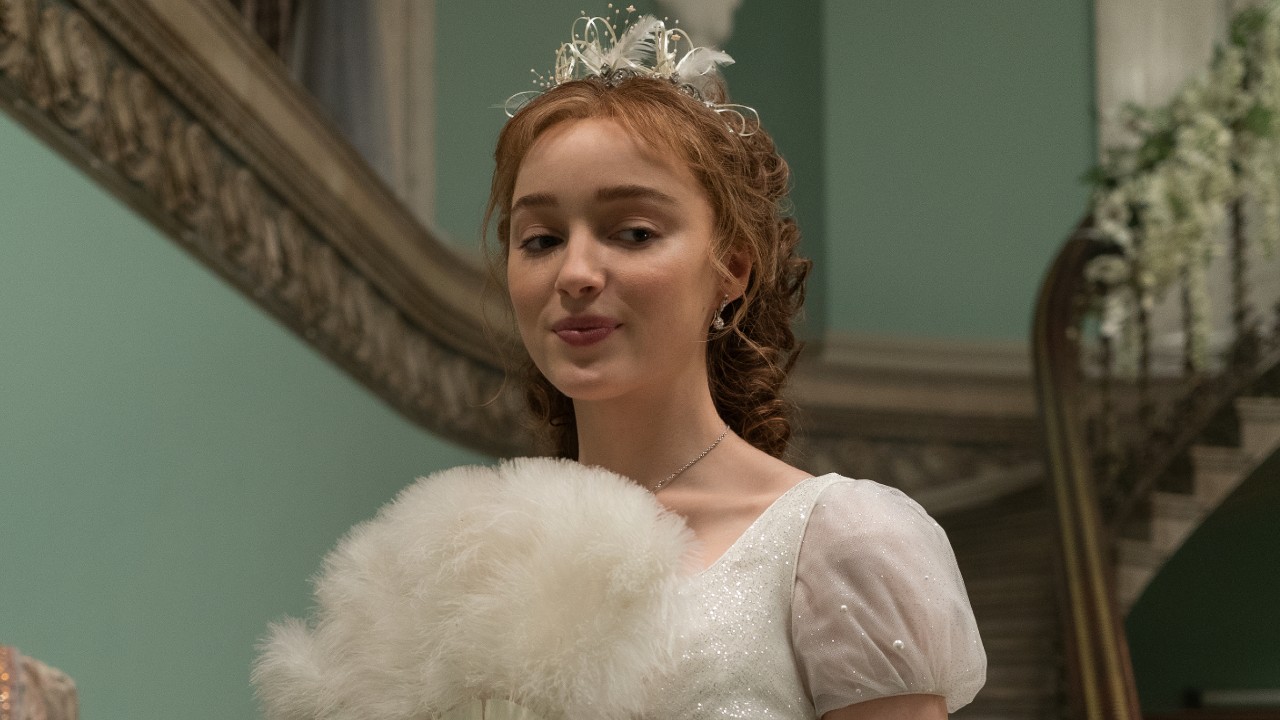 Phoebe Dynevor as Daphne Bridgerton holding a fan up. 