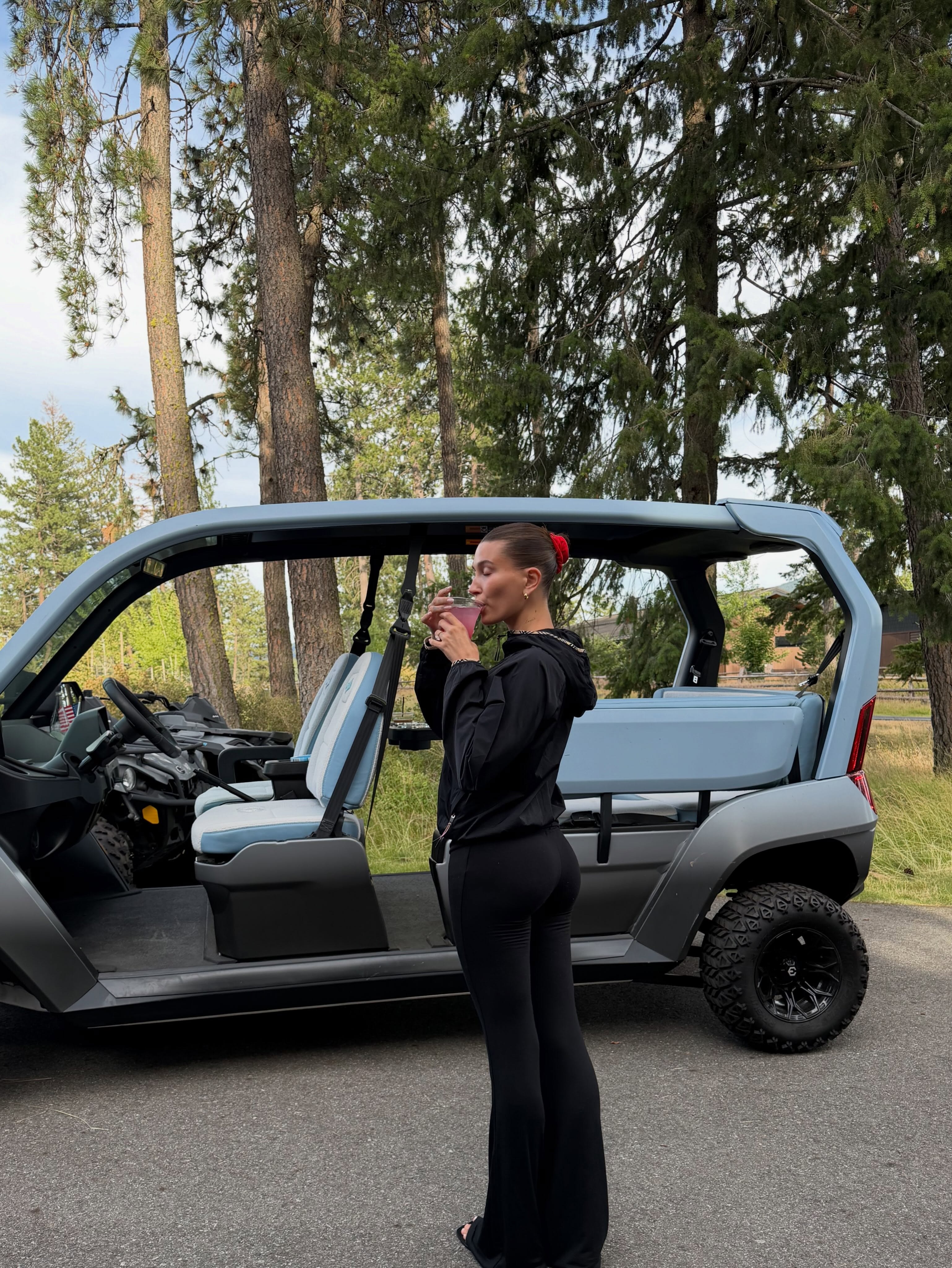 Hailey Bieber wears flared leggings with sandals and a black hoodie.