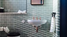 A small bathroom with light green tiles