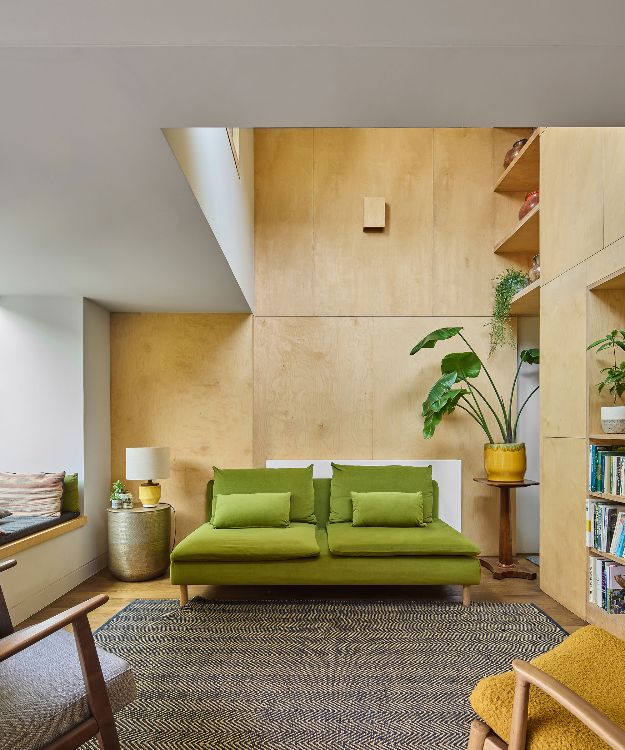 renovated house with double-height living space, plywood walls and a green sofa