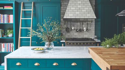 Kitchen with teal cabinets, marble countertops, and a tiled splashback with matching extractor hood