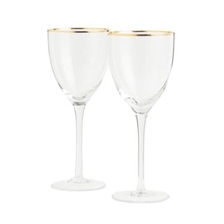 two stemmed transparent wine glasses with gold rims