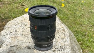 Sony FE 16-35mm F2.8 GM II lens stood outdoors on a rock