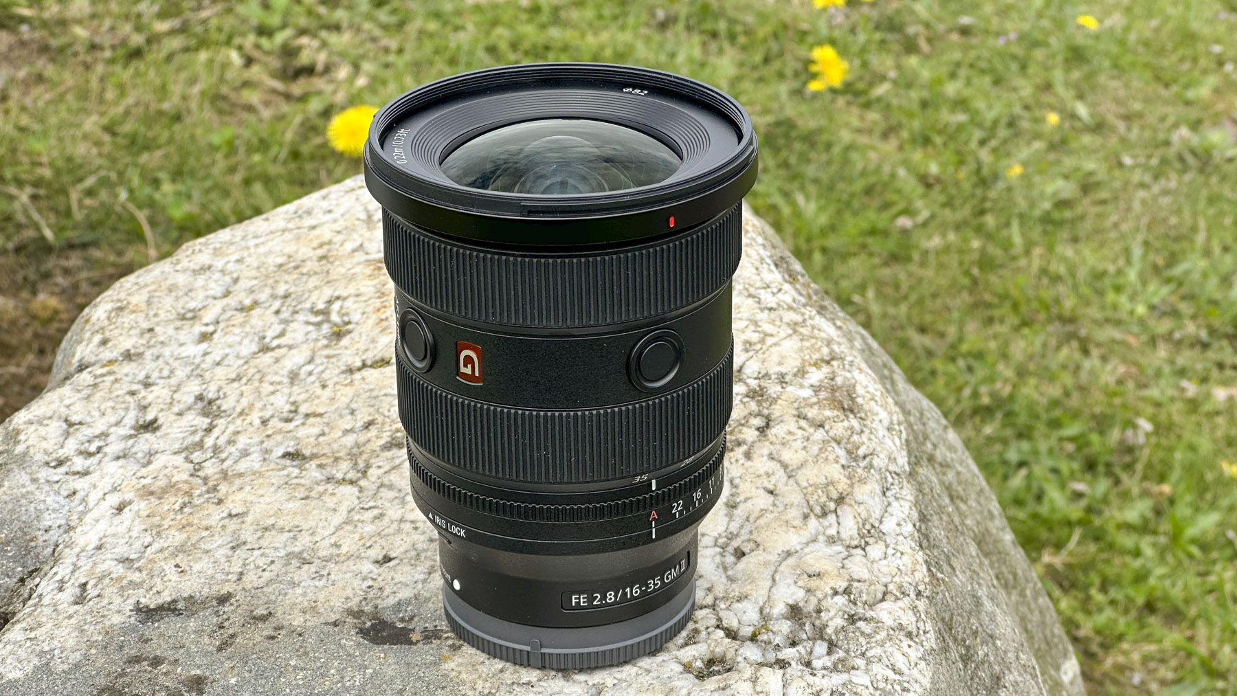 Sony FE 16-35mm F2.8 GM II lens stood outdoors on a rock