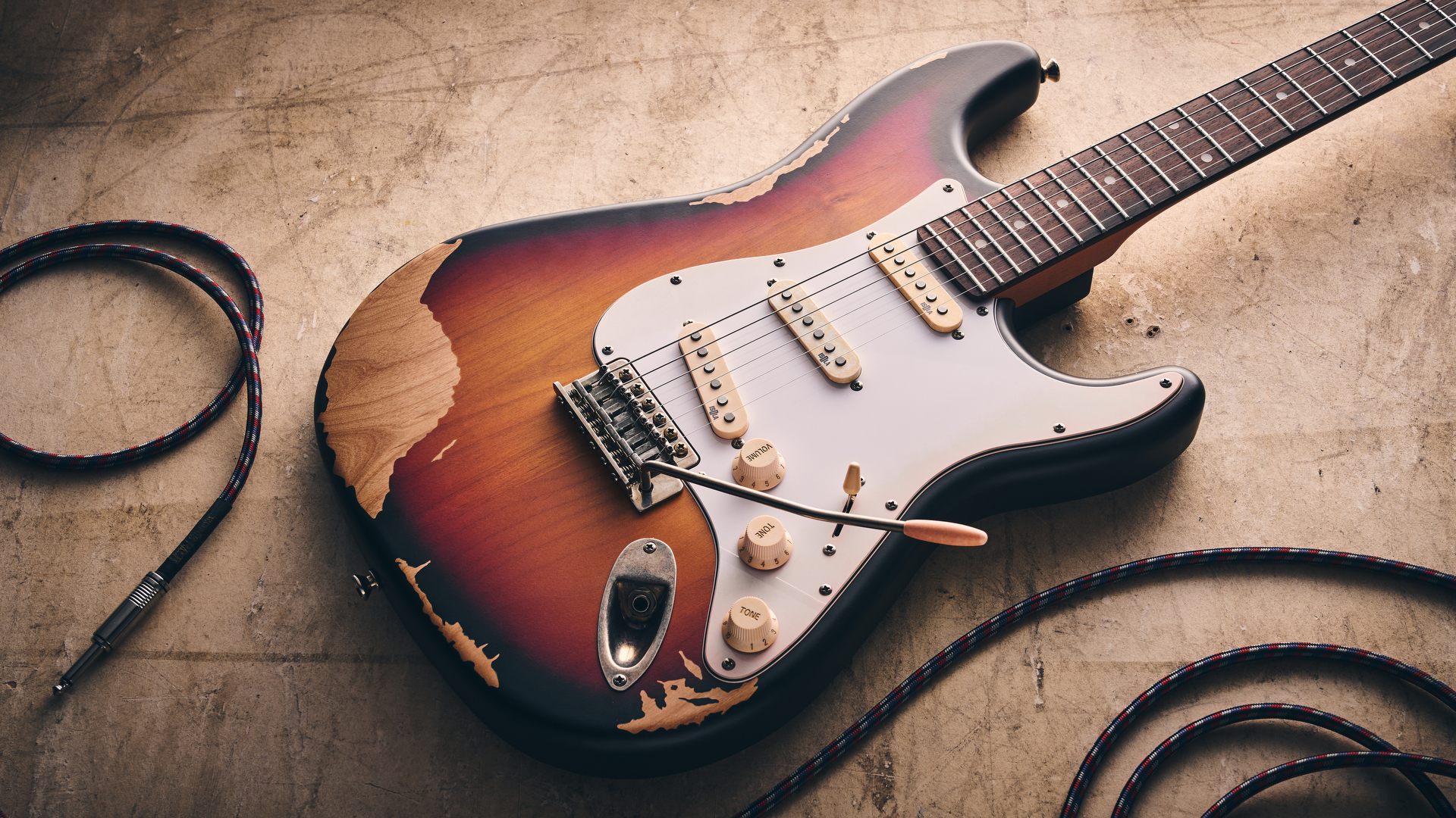 A Harley Benton ST-62HA electric guitar on a concrete floor with a guitar cable nearby