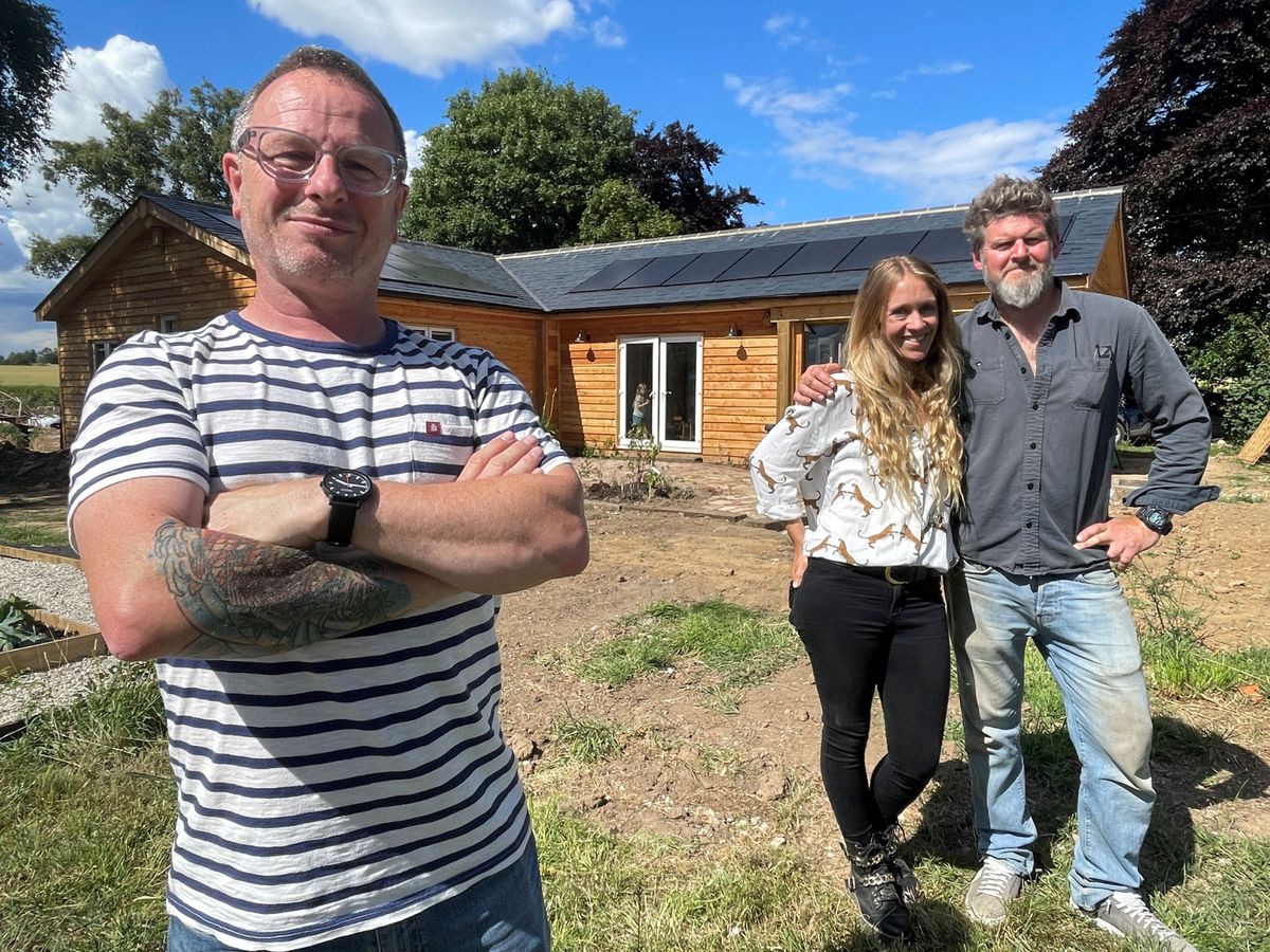 Mark Millar stood next to couple Lucy and Mike, in front of their new self built timber framed home.