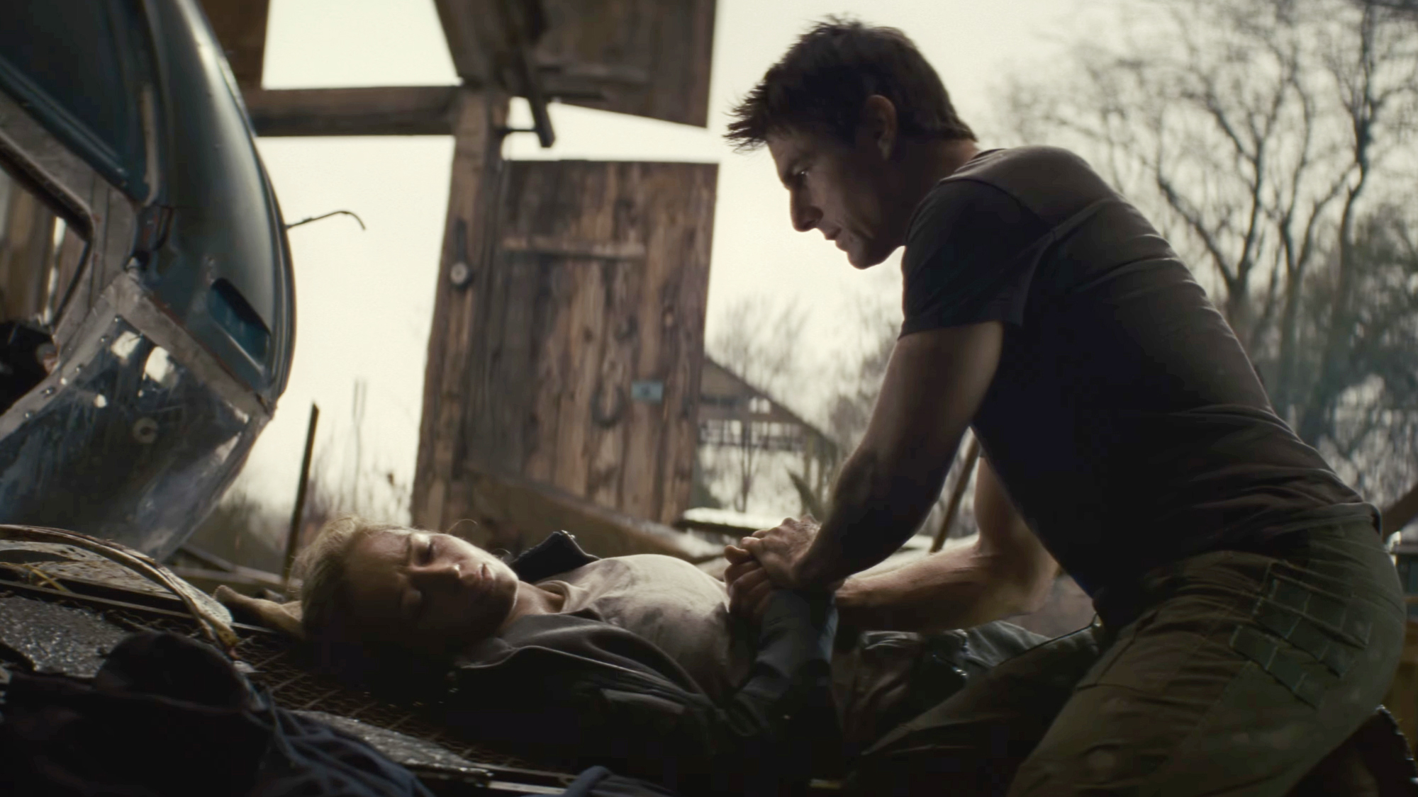 Tom Cruise kneels next to a hurt Emily Blunt in Edge of Tomorrow (2014).