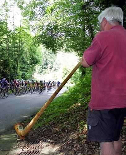 The peloton is greeted by a blast from a horn player