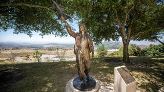 bronze statue of sally rise reaching up with her right hand to hold a scale model of the space shuttle challenger.