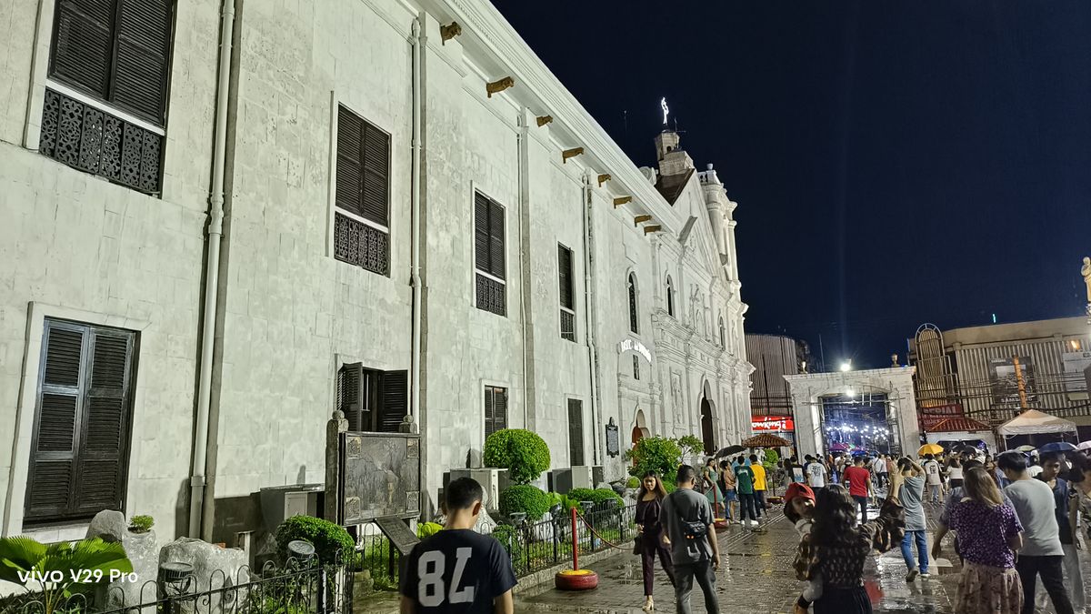 People walking in the rain outside a church, seeking shelter from the downpour